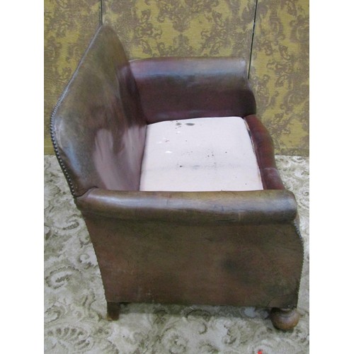 1275 - An early 20th century low two seat sofa upholstered in brown leather with studded detail, swept and ... 