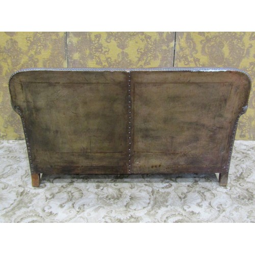 1275 - An early 20th century low two seat sofa upholstered in brown leather with studded detail, swept and ... 