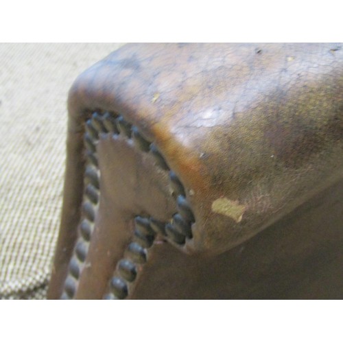 1275 - An early 20th century low two seat sofa upholstered in brown leather with studded detail, swept and ... 