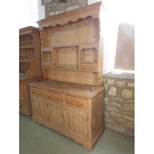 1286 - A traditional stripped pine kitchen dresser, the base enclosed by three fielded panelled doors benea... 