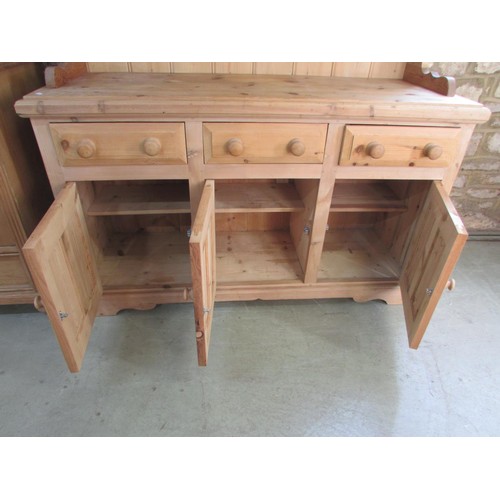 1286 - A traditional stripped pine kitchen dresser, the base enclosed by three fielded panelled doors benea... 