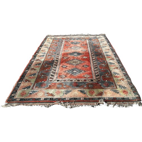 1605 - A Turkey carpet with a central panel with five diamond medallions on a pink and light blue ground, 3... 