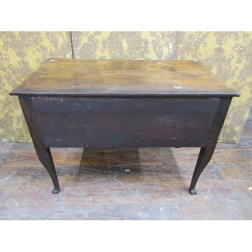 1364 - A Georgian oak side table with three drawers over a central kneehole on shaped supports, 105cm wide