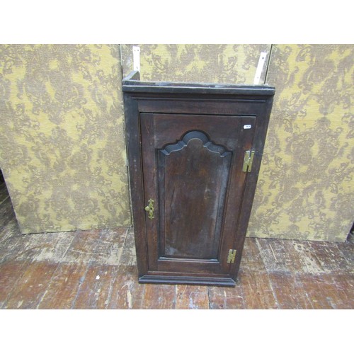 1452 - An 18th century oak wall mounted cupboard enclosed by a shaped and fielded panelled door with elm li... 