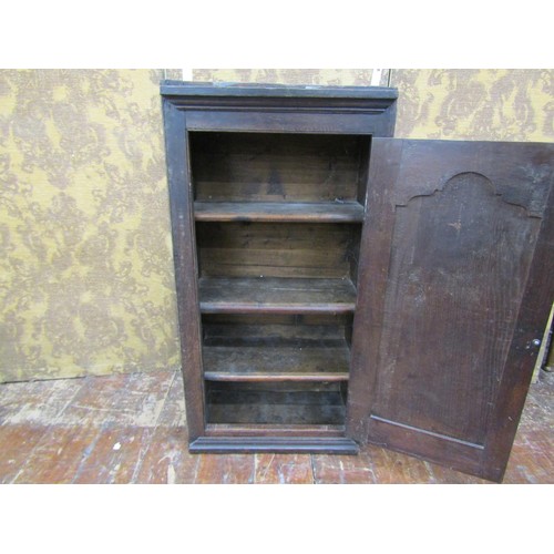 1452 - An 18th century oak wall mounted cupboard enclosed by a shaped and fielded panelled door with elm li... 