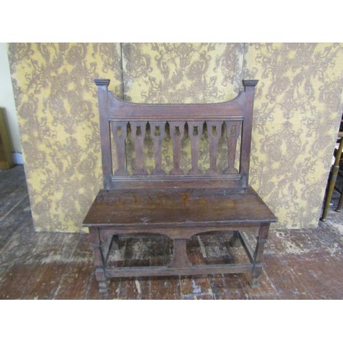 1455 - An Arts & Crafts oak hall settle with repeating vase shaped splats over a solid seat on shaped suppo... 