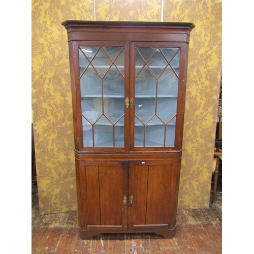 1473 - A late Georgian oak corner cupboard freestanding, the upper section with astragal glazed panel doors... 