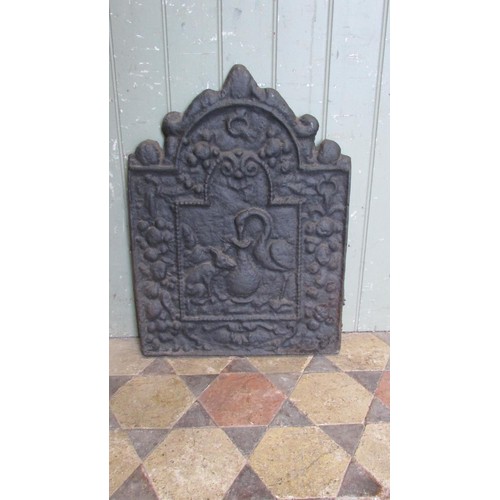 1063 - A small but heavy cast iron fire back of stepped arched form with raised relief detail, 60cm high x ... 