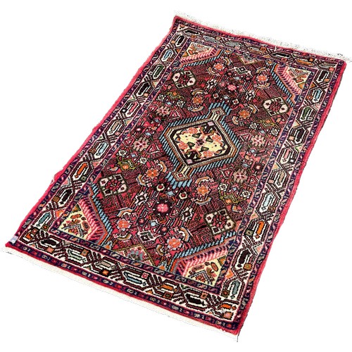 1610 - A small Persian rug with a lozenge shaped central medallion and stylised flowers, 125cm x 78cm appro... 