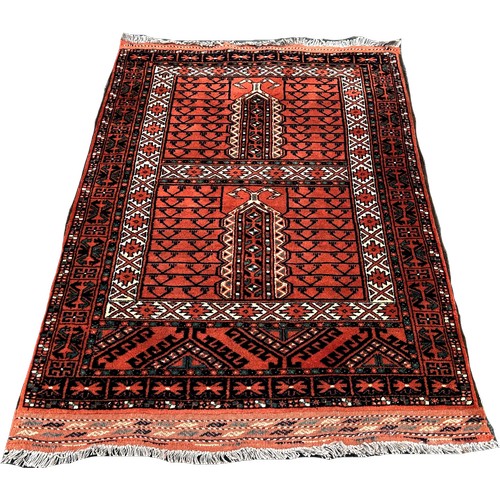 1635 - A Persian rug with mirrored geometric designs on a rusty red ground, 160cm x 55cm approximately