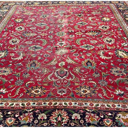 1649 - A large country house Persian wool carpet with a large all over floral pattern on a red ground with ... 