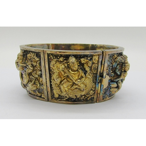 280A - Antique Indian gilt metal hinged cuff bracelet with six embossed panels depicting deities, 71g