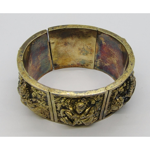 280A - Antique Indian gilt metal hinged cuff bracelet with six embossed panels depicting deities, 71g