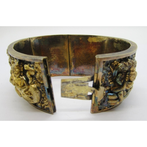 280A - Antique Indian gilt metal hinged cuff bracelet with six embossed panels depicting deities, 71g