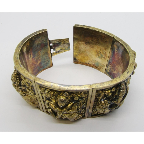 280A - Antique Indian gilt metal hinged cuff bracelet with six embossed panels depicting deities, 71g