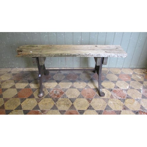 1059 - An antique cast iron bench base with swept supports united by a simple steel rod beneath an associat... 