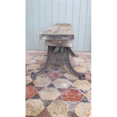 1059 - An antique cast iron bench base with swept supports united by a simple steel rod beneath an associat... 