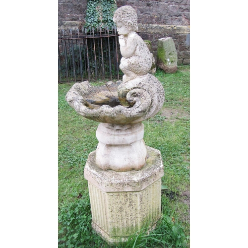 1023 - A weathered cast composition stone bird bath in the form of a shell with pan surmount and raised on ... 