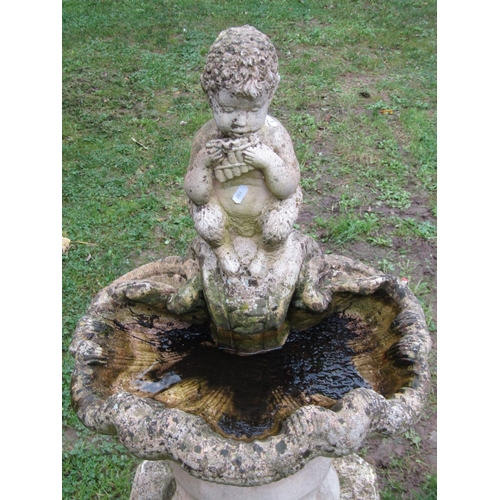 1023 - A weathered cast composition stone bird bath in the form of a shell with pan surmount and raised on ... 