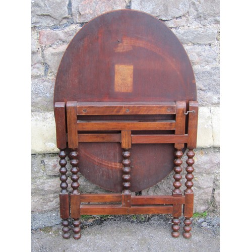 1332 - Mahogany folding coaching type table on turned bobbin supports, with applied paper registration vers... 