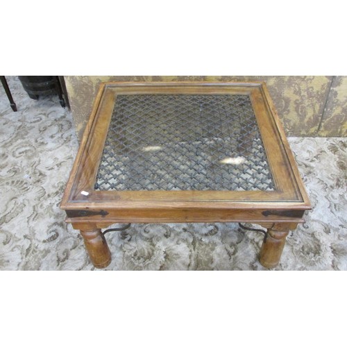 1288 - A low Indian hardwood occasional table with decorative iron work lattice panelled top with glass cov... 