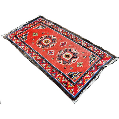 1735 - A Tibetan wool carpet with circular floral patterns on an orange ground180cm x 95cm approximately