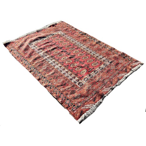 1741 - A Turkoman carpet with a central panel of guls on a brick red ground, 190cm x 130cm approximately