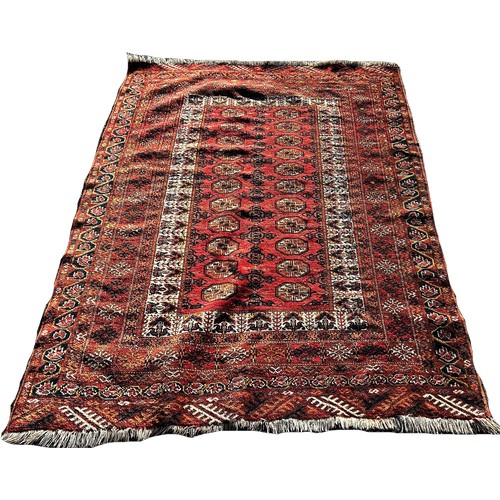 1741 - A Turkoman carpet with a central panel of guls on a brick red ground, 190cm x 130cm approximately