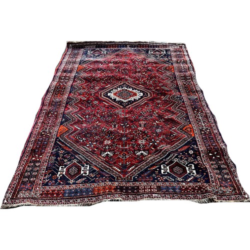 1736 - A Persian Carpet with a central radiating medallion with a field of stylised flowers on a red ground... 