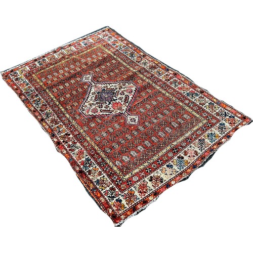 1737 - A worn Persian rug with an extended lozenge medallion on a brick red field 120 x 170cm