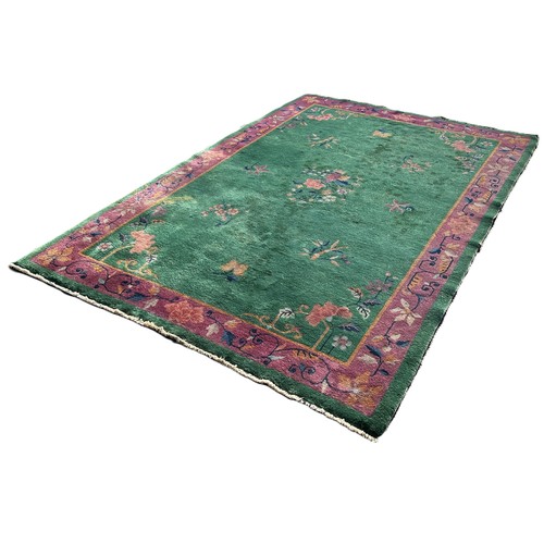 1742 - A Chinese design carpet with sprays of flowers on an ever green ground and a purple border, 275cm x ... 