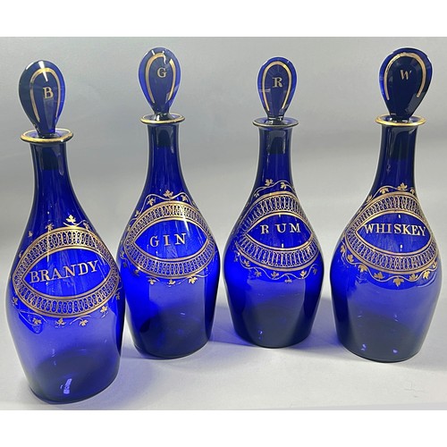 279 - A set of four ‘Indian Club’ Bristol Blue Decanters,  (Brandy, Rum, Gin, and Whiskey), set in a Matth... 