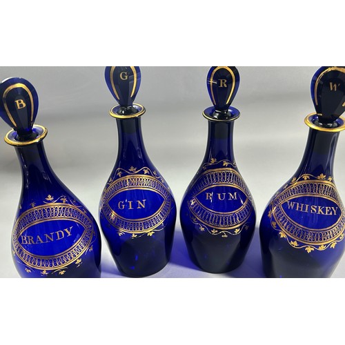 279 - A set of four ‘Indian Club’ Bristol Blue Decanters,  (Brandy, Rum, Gin, and Whiskey), set in a Matth... 