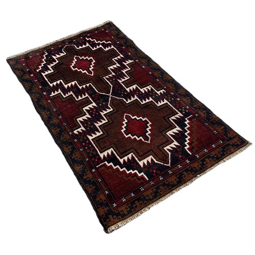 1745 - A Baluchi rug with red and blue zig-zag medallions 140cm x 86cm approximately