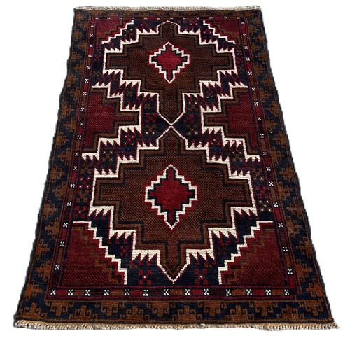 1745 - A Baluchi rug with red and blue zig-zag medallions 140cm x 86cm approximately