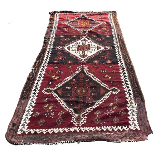 1739 - A Kilim with three large diamond shaped medallions on a dark red field.  130 x 336cm approximately