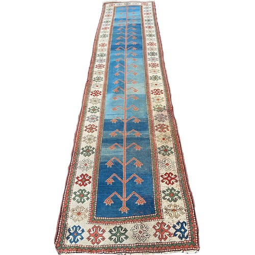 1761 - A Middle Eastern runner with a central abstract pattern on a blue ground, 400cm x 90cm approx.