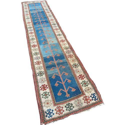 1761 - A Middle Eastern runner with a central abstract pattern on a blue ground, 400cm x 90cm approx.