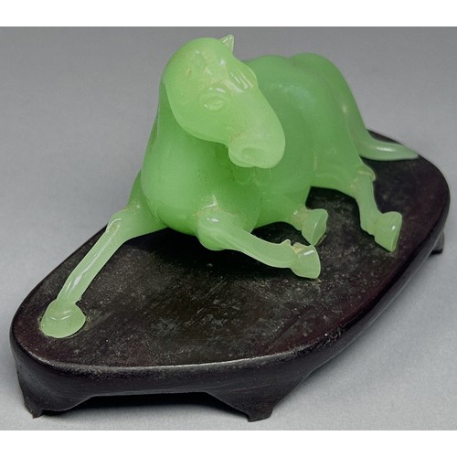 412 - A vintage jade coloured Chinese Peking glass horse, recumbent on hardwood base