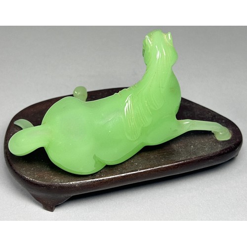 412 - A vintage jade coloured Chinese Peking glass horse, recumbent on hardwood base