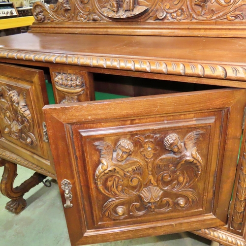 1169 - A continental walnut buffet with raised back over a pair of panelled doors with carved, mask cornuco... 