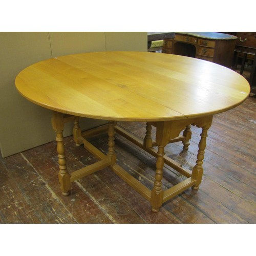 1330 - A large light oak old English style oval drop leaf dining table with gateleg action, raised on eight... 