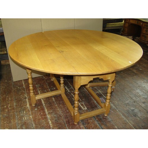 1330 - A large light oak old English style oval drop leaf dining table with gateleg action, raised on eight... 