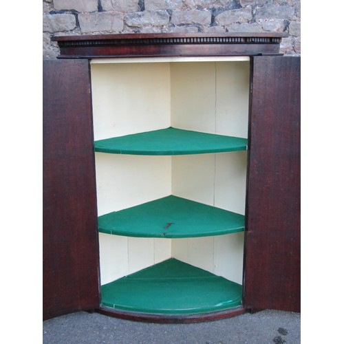 1340 - A Georgian oak bow fronted hanging corner cupboard enclosed by to doors with polished brass fittings... 