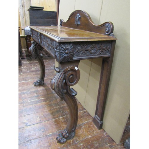 1415 - A Victorian oak hall table raised on shaped supports with lions paw feet, the carved frieze enclosin... 