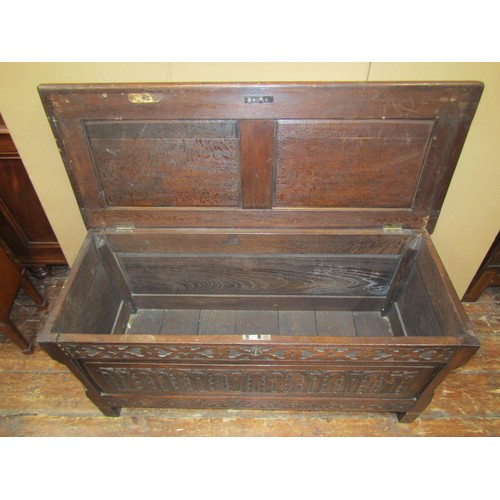 1453 - An old English panelled oak coffer with rising lid, the front elevation with repeating geometric det... 