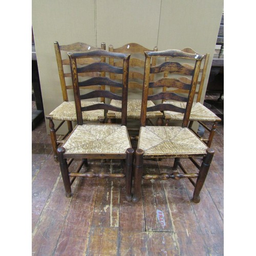 1473 - A collection of five Georgian ashwood country made ladderback chairs on turned supports with rush se... 