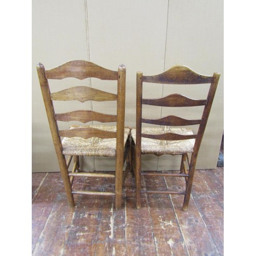 1473 - A collection of five Georgian ashwood country made ladderback chairs on turned supports with rush se... 