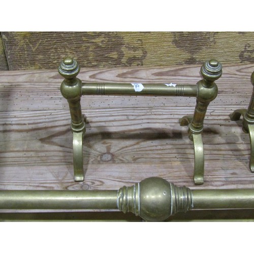 1100 - A brass fender with turned and scrolled rail, together with an associated brass companion set, and a... 