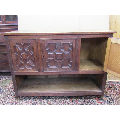 1432 - An Edwardian oak buffet in the Jacobean style enclosed by three panelled doors with open shelf below... 